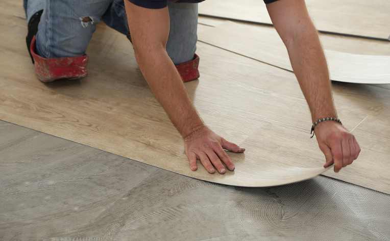 professional installer laying down luxury vinyl plank on concrete subfloor